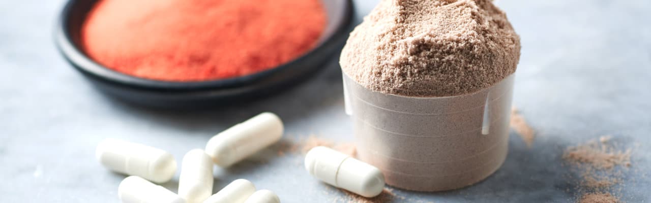 Proteinpulver im Messlöffel mit Kapseln
