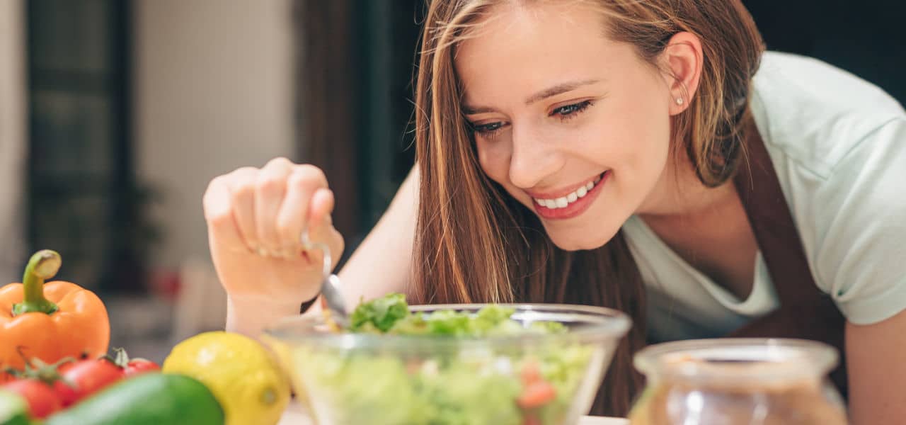 Lächelnde Frau bereitet einen frischen Salat zu