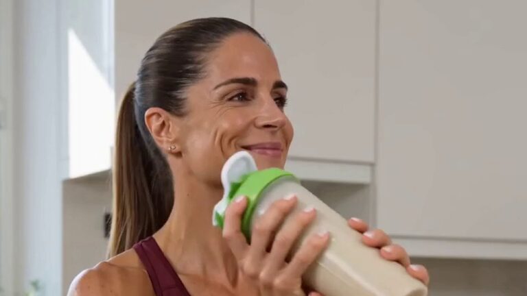 Frau trinkt einen veganen Proteinshake aus dem Shaker in der Küche